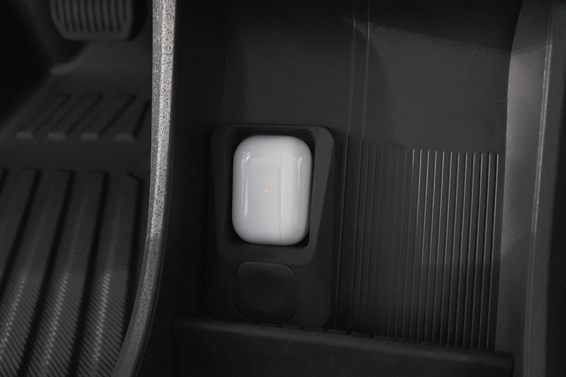 JOWUA Taiwan 多功能無線充電底座+Apple Watch 無線充電器組合放置在黑色紋理表面和地墊的汽車車廂中,其白色外殼上有一個小指示燈,可與 AirPods 無線充電器相容。.