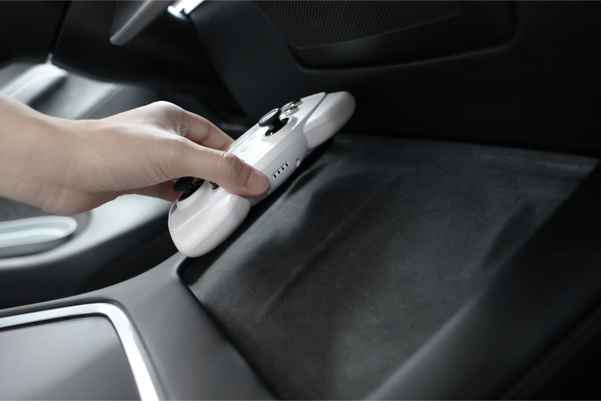 一隻手將 JOWUA Taiwan 無線充電雙搖桿組合 (Model 3/Y) 放在車內的黑色表面上,突顯出特斯拉手套箱線集器的相容性和 Switch 2 支援。.