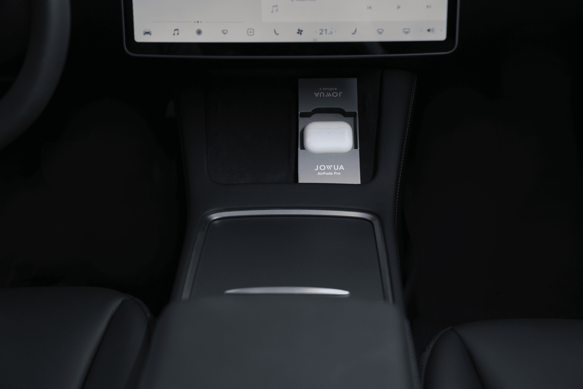 在這款 Model 3 的時尚內裝中,有一個無線充電板為標有「JOWUA Taiwan」的白色耳機充電。儀表板螢幕的簡約設計與黑色座椅和控制台完美搭配。.