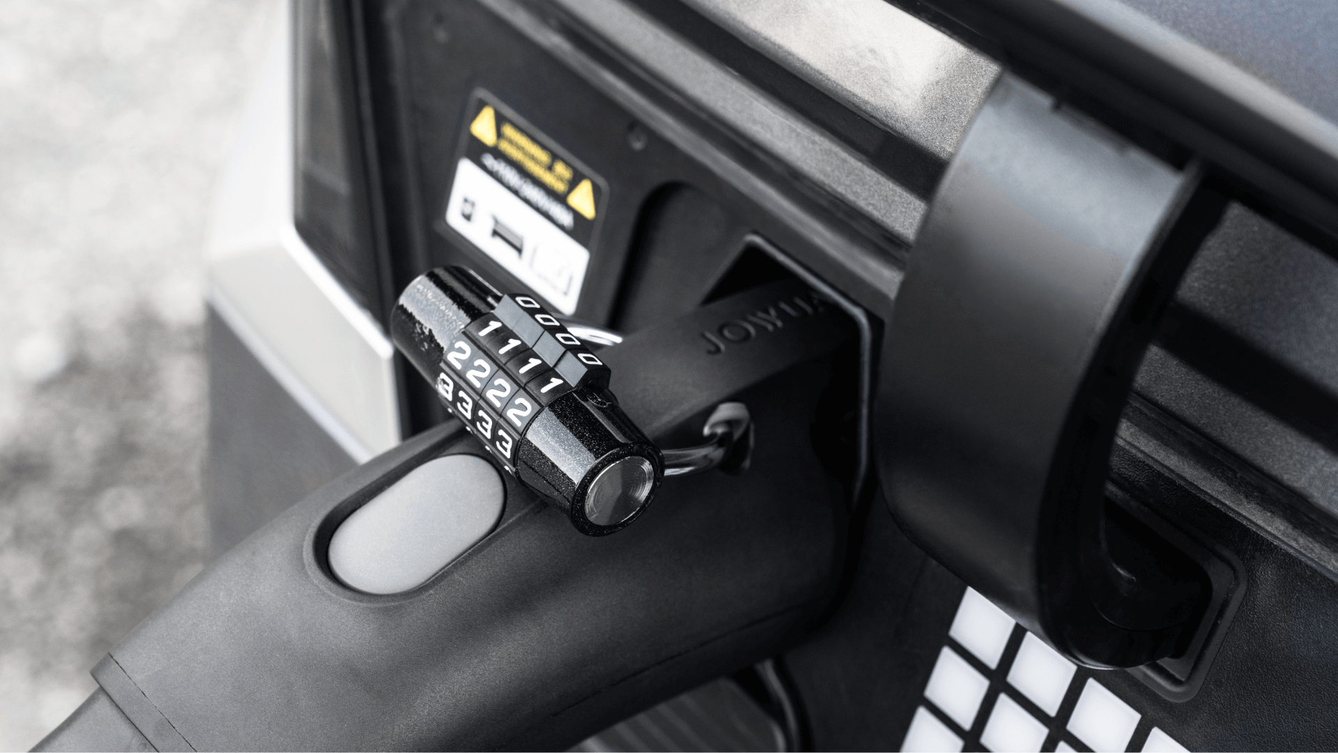 台灣 JOWUA 的 CCS1 快慢充萬用組充電插頭的灰階特寫,用顯示數字的密碼鎖固定。此圖像突出顯示了插頭連接到充電埠時與第三方網路的兼容性。.