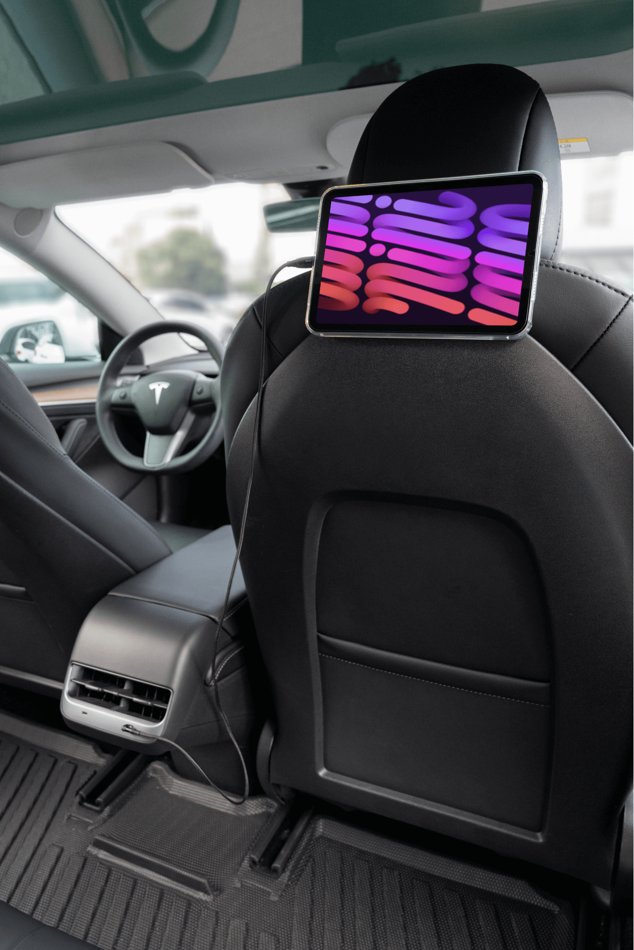 特斯拉 Model 3中控配備 JOWUA 台灣 USB-C 車用磁吸線,可快速充電。車內採用黑色皮革座椅,設計現代,座椅背面安裝有顯示彩色抽象形狀的平板電腦。.