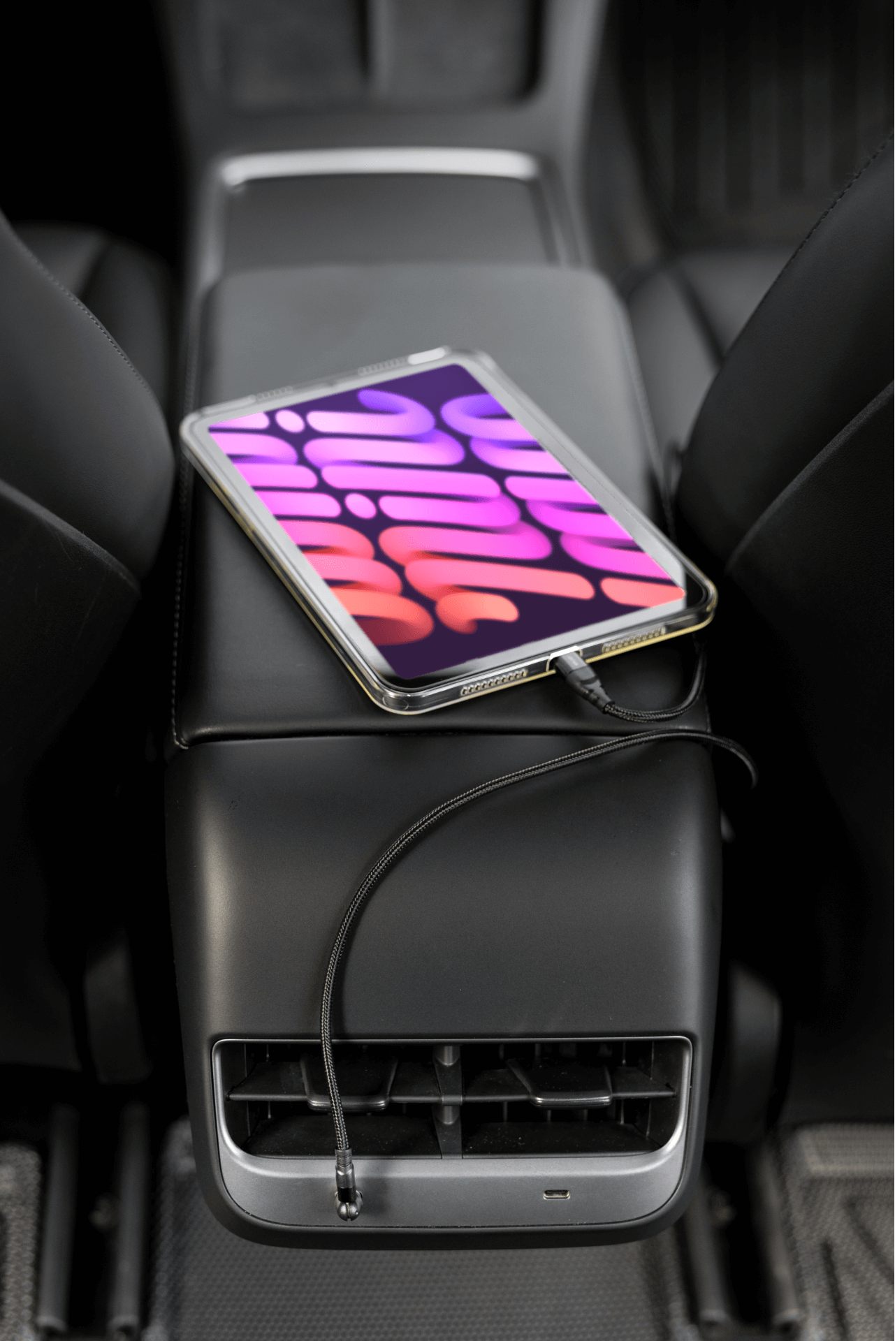 Model 3中控上,一台擁有彩色抽象螢幕的平板電腦與JOWUA台灣USB-C車用磁吸線連接。該車的內部採用黑色座椅和控制台下方的通風口。.
