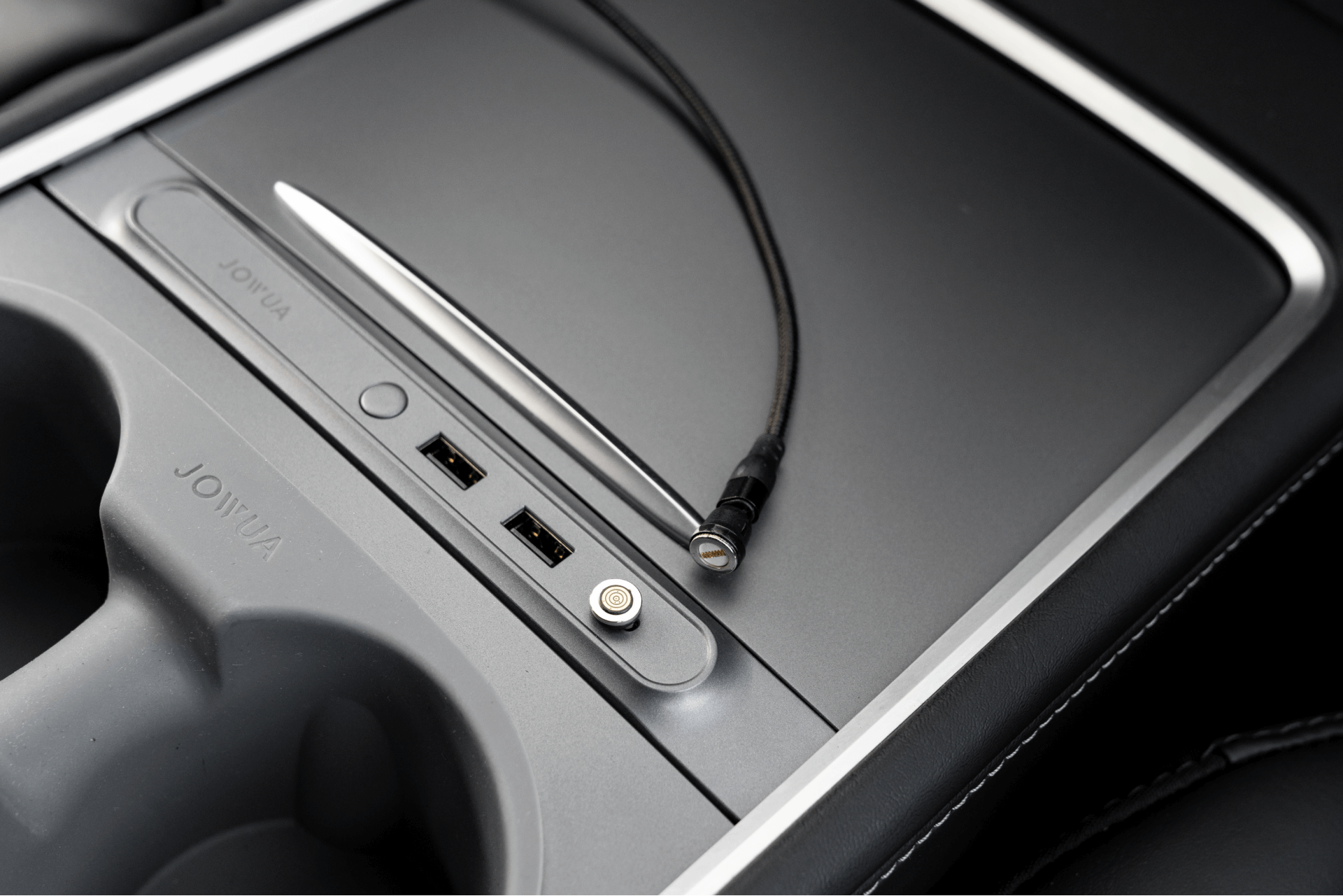 Model 3 中控台特寫,配備兩個 USB 連接埠、USB-C PD快充、筆、充電埠和捲曲電纜。光滑的金屬控制台在杯架附近帶有 JOWUA 台灣標誌,並配有 USB-C 車用磁吸線(0.4M/1M/1.8M)。.