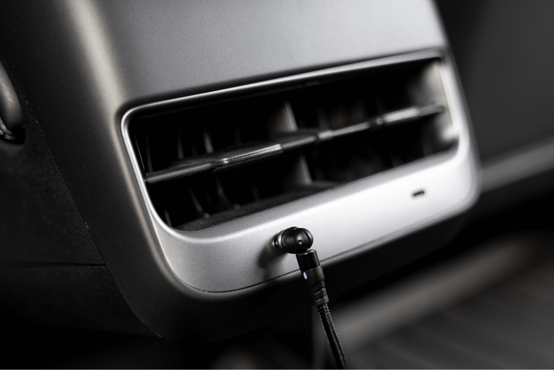 JOWUA台灣USB-C車用磁吸線(0.4M/1M/1.8M)插入汽車通風口的特寫,展示USB-C PD快充。該設備巧妙地融入了現代室內裝飾,並具有與 Model 3中控設計類似的金屬飾面。.
