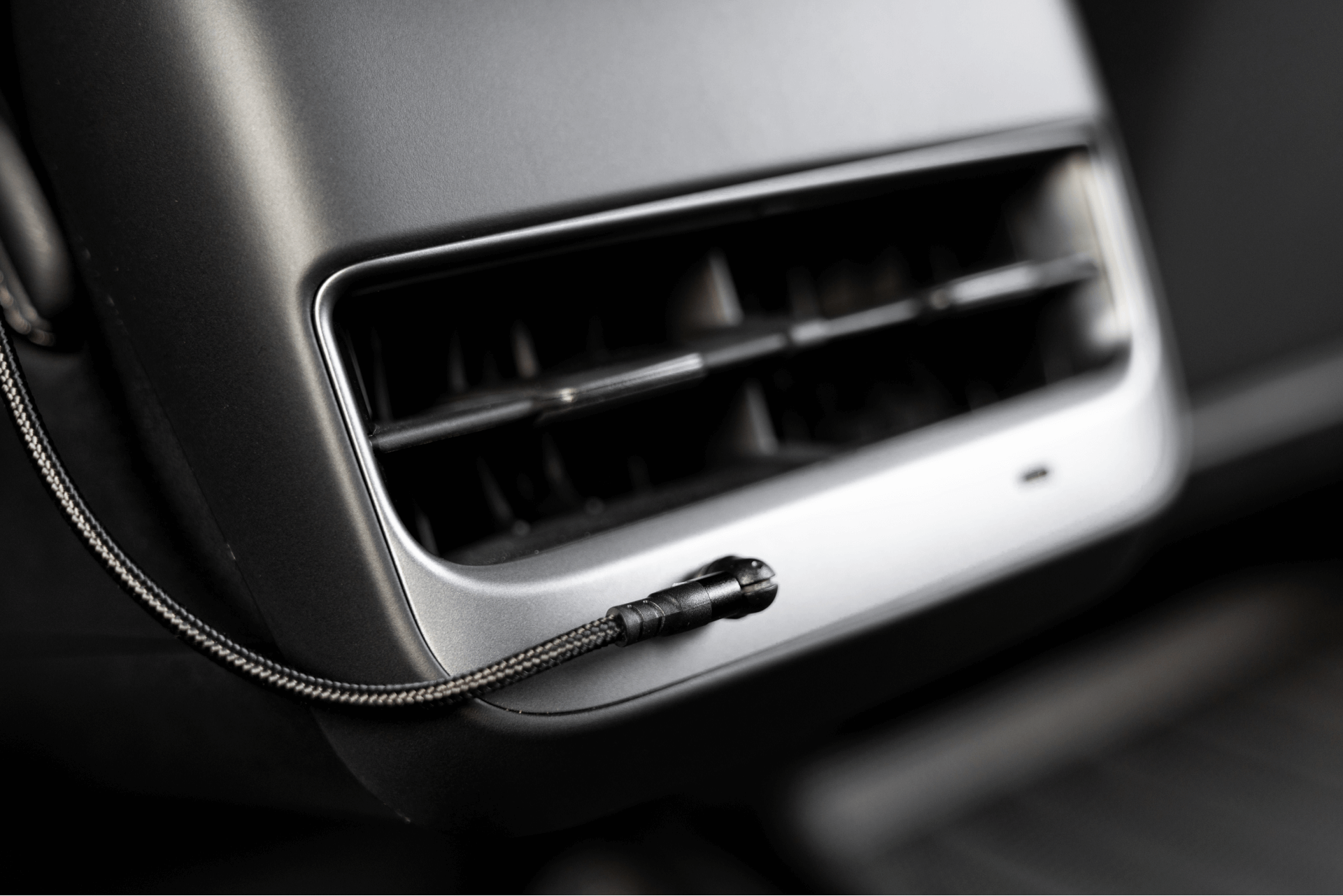 汽車通風口特寫,採用 JOWUA 台灣時尚的 USB-C 車用磁吸線(0.4M/1M/1.8M),非常適合 Model 3 中控整合。銀色和黑色的設計與內裝相得益彰,表明可以輕鬆透過潛在的 USB-C PD快充功能實現連接。.