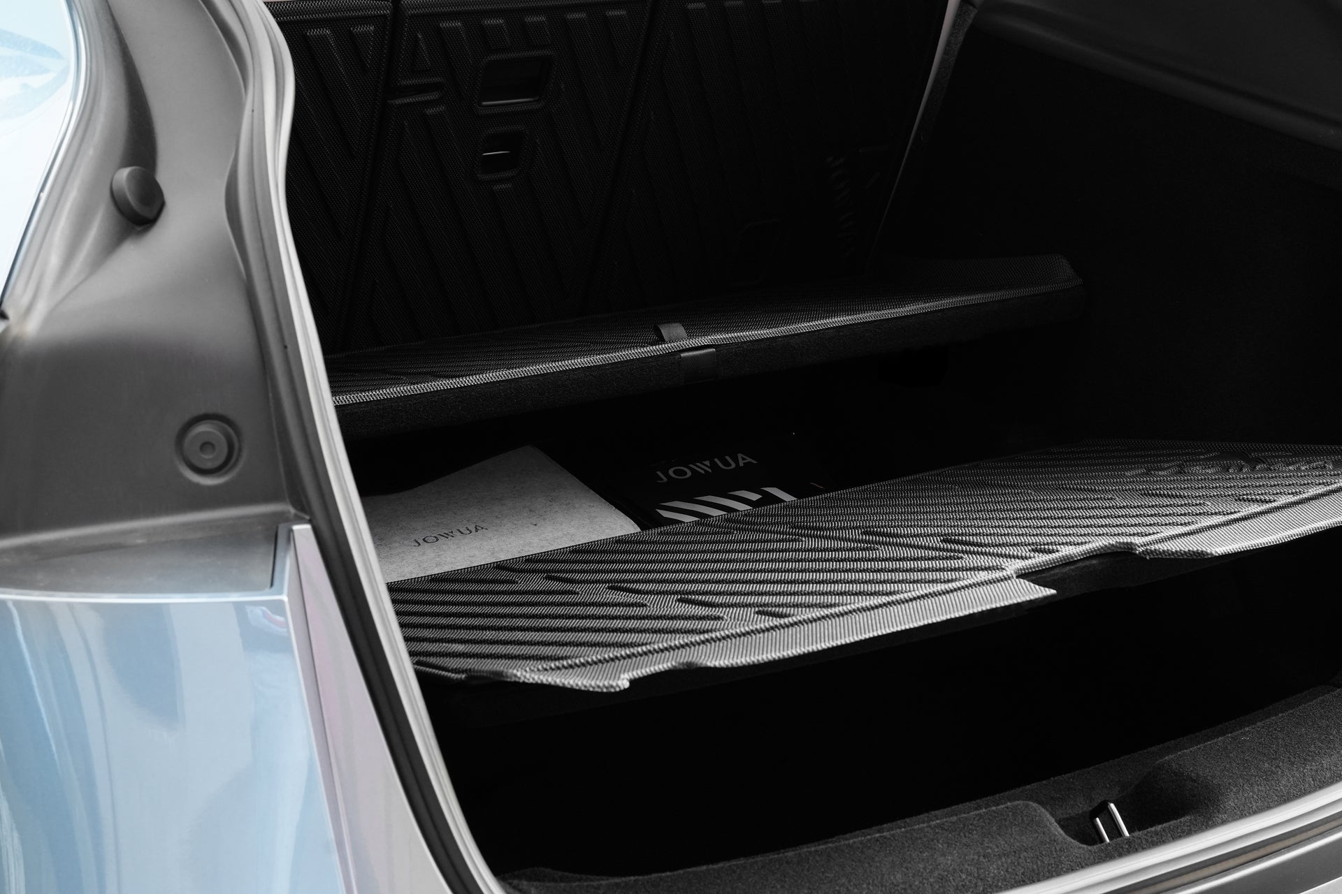 打開汽車後備箱，可看到多個儲物格，下方儲物格內有電墊專案【Model Y 煥新版｜交車禮包】，來自 JOWUA Taiwan，是特斯拉 Model Y 車用收納的理想選擇。.