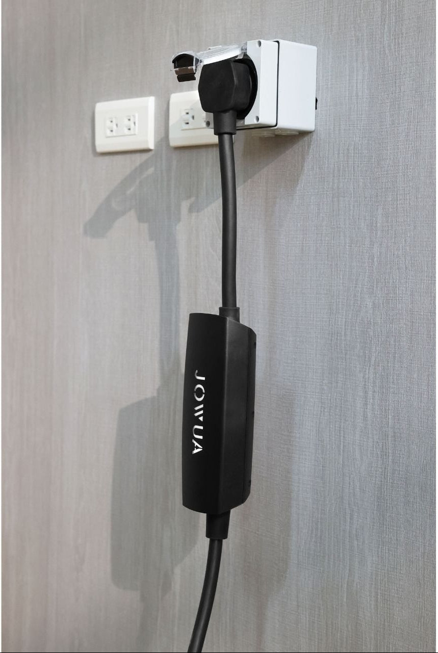 黑色 JOWUA 台灣 NEMA 14-50 轉接器充電線，採用 40A 高規格設計，插入牆壁插座。灰色的牆壁展示了兩個白色的電源插座。.
