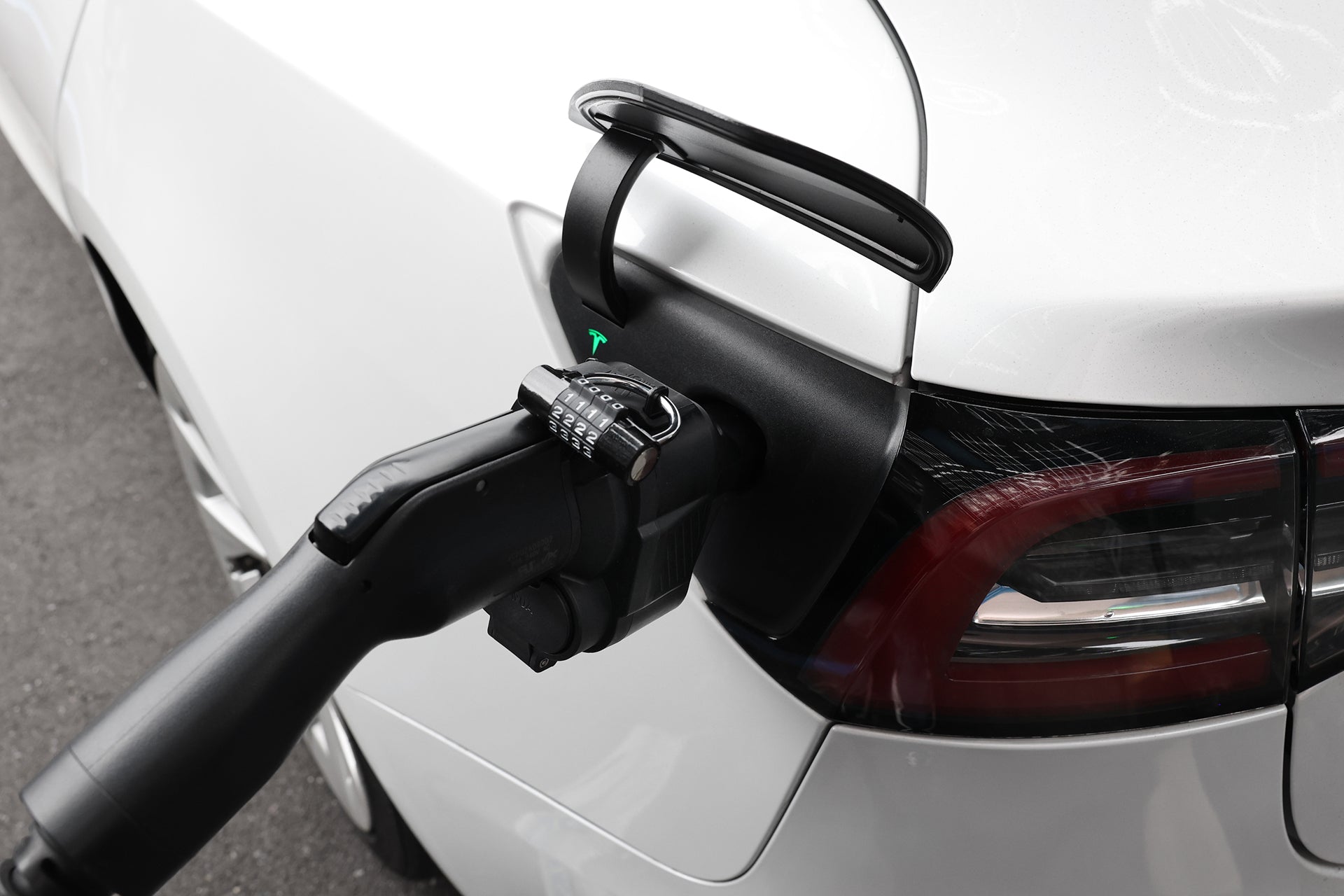 使用 JOWUA Taiwan CCS1 to NACS (TPC) DC & AC 快慢充轉接頭為白色汽車後方充電埠充電的特寫。.