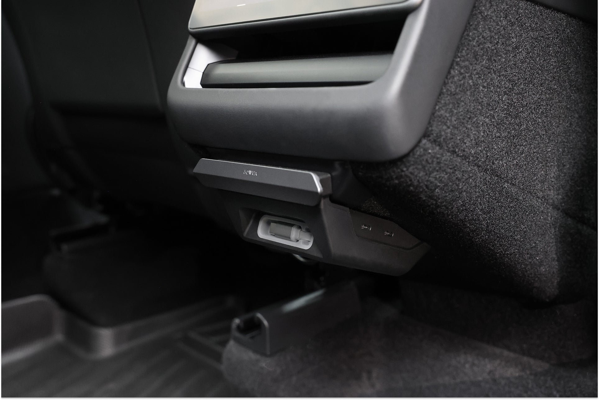 台灣 JOWUA 130W LED 後排專用 HUB (Model 3/Y 煥然一新版) 特寫，具備 Type-C 充電功能，安裝於後中控台；可看到深色地毯與座椅。.