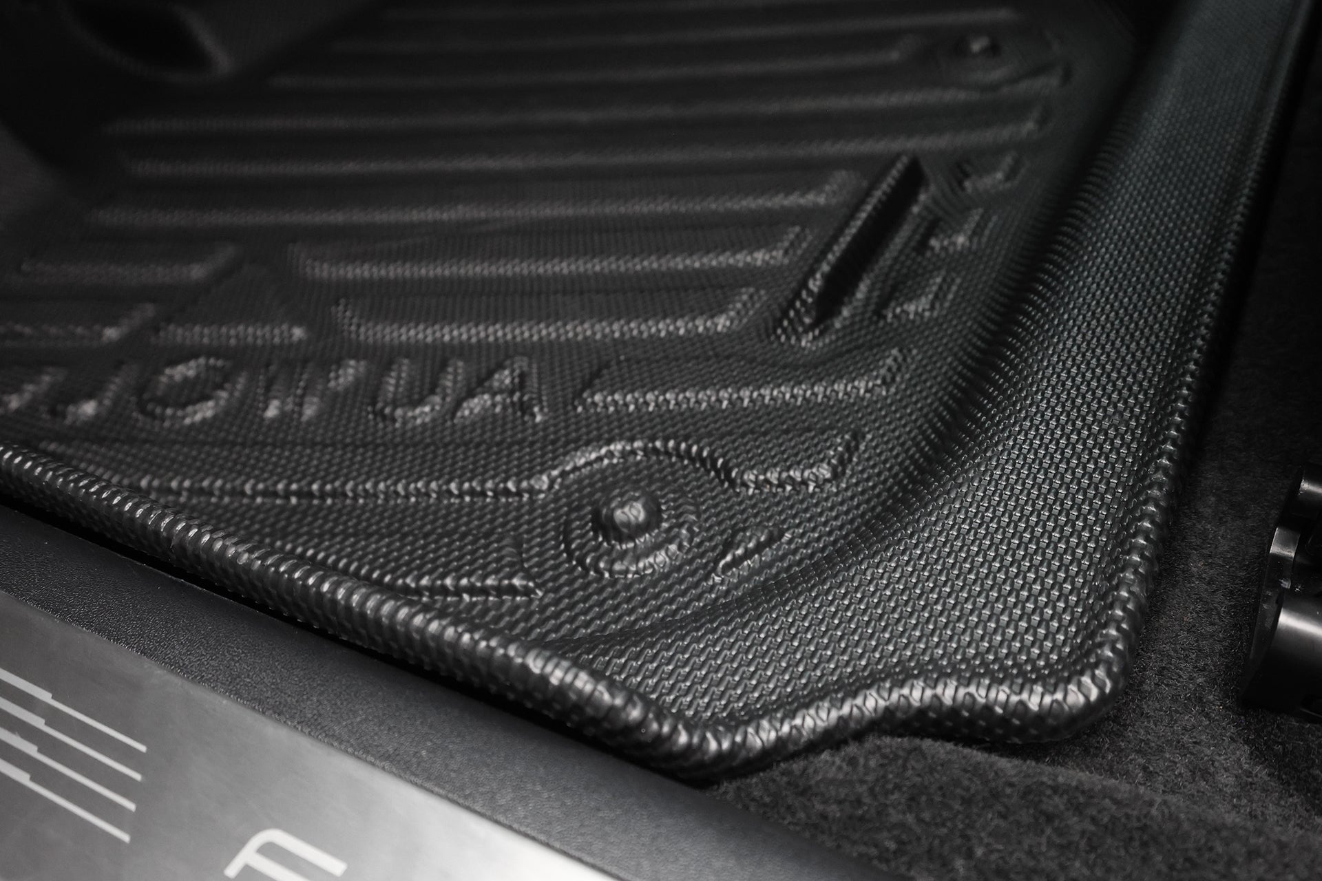 特寫黑色 JOWUA Taiwan 立體防水腳踏墊 (Foxtron Bria) 車用墊，有溝槽、凸起邊緣及專利止擋收納設計，全方位防護，保障車內不受髒污及濕氣侵害。.