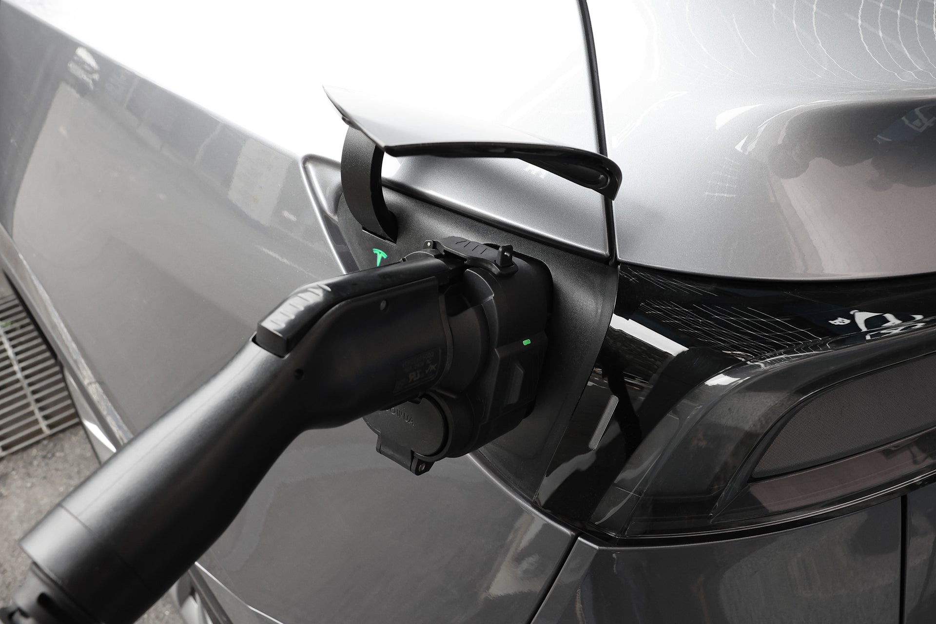 使用 JOWUA Taiwan CCS2 DC & AC 快慢充萬用組充電的銀色汽車特寫，顯示 CCS2 轉接頭與連接線插入連接埠，突顯電動車快充科技。.