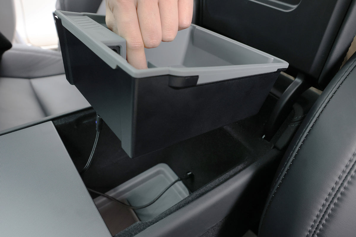 一隻手將中控台托盤放進 Model Y 車內，並將 JOWUA 台灣 Power HUB 中控組合（Model Y, 2025+ 煥新版）的充電線連接至車內插孔。.