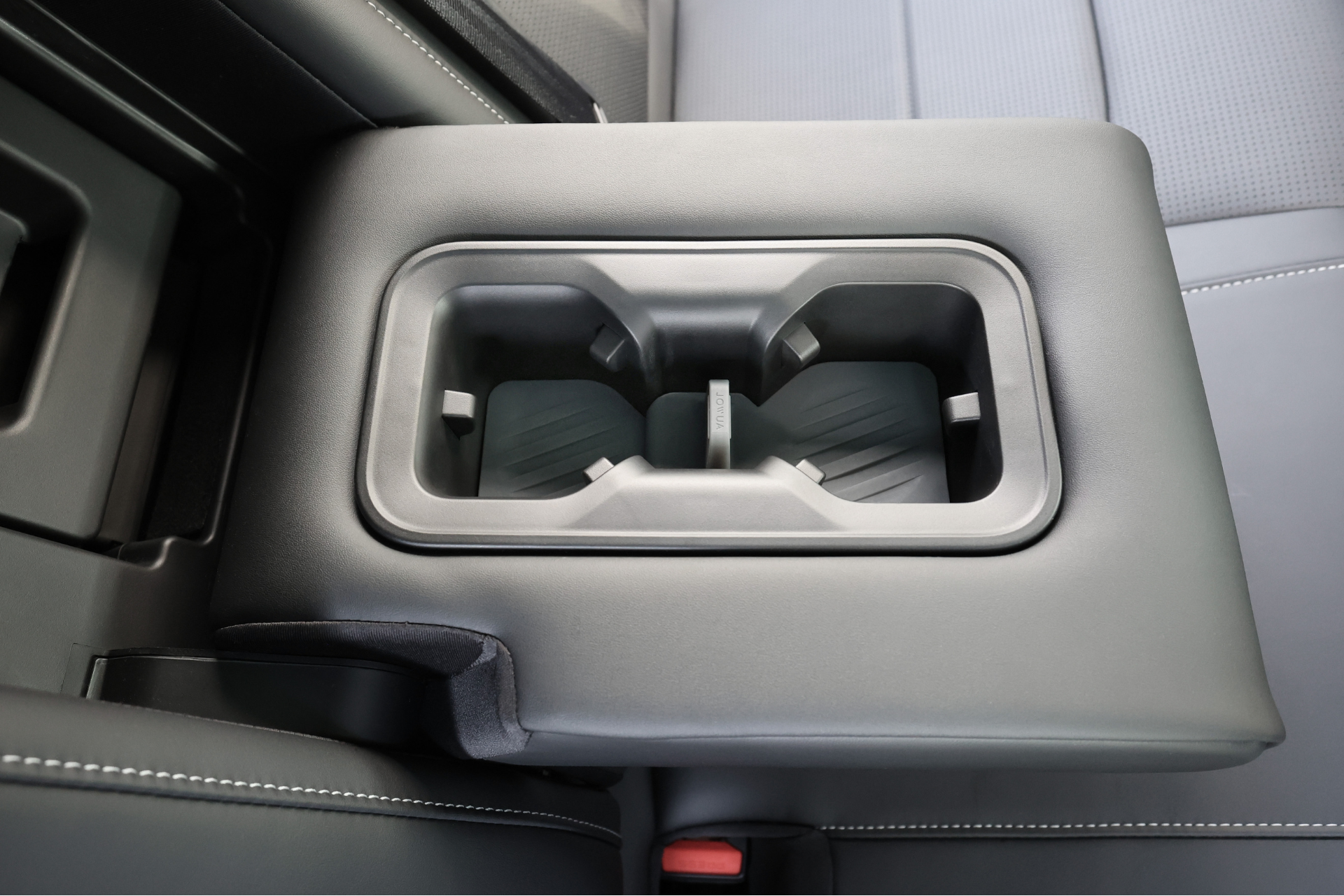 台灣 JOWUA 後排杯墊 (Foxtron Bria) 特寫，設有雙杯架和 矽膠杯墊，套在黑灰色後排座椅襯墊上，縫線清晰可見。.