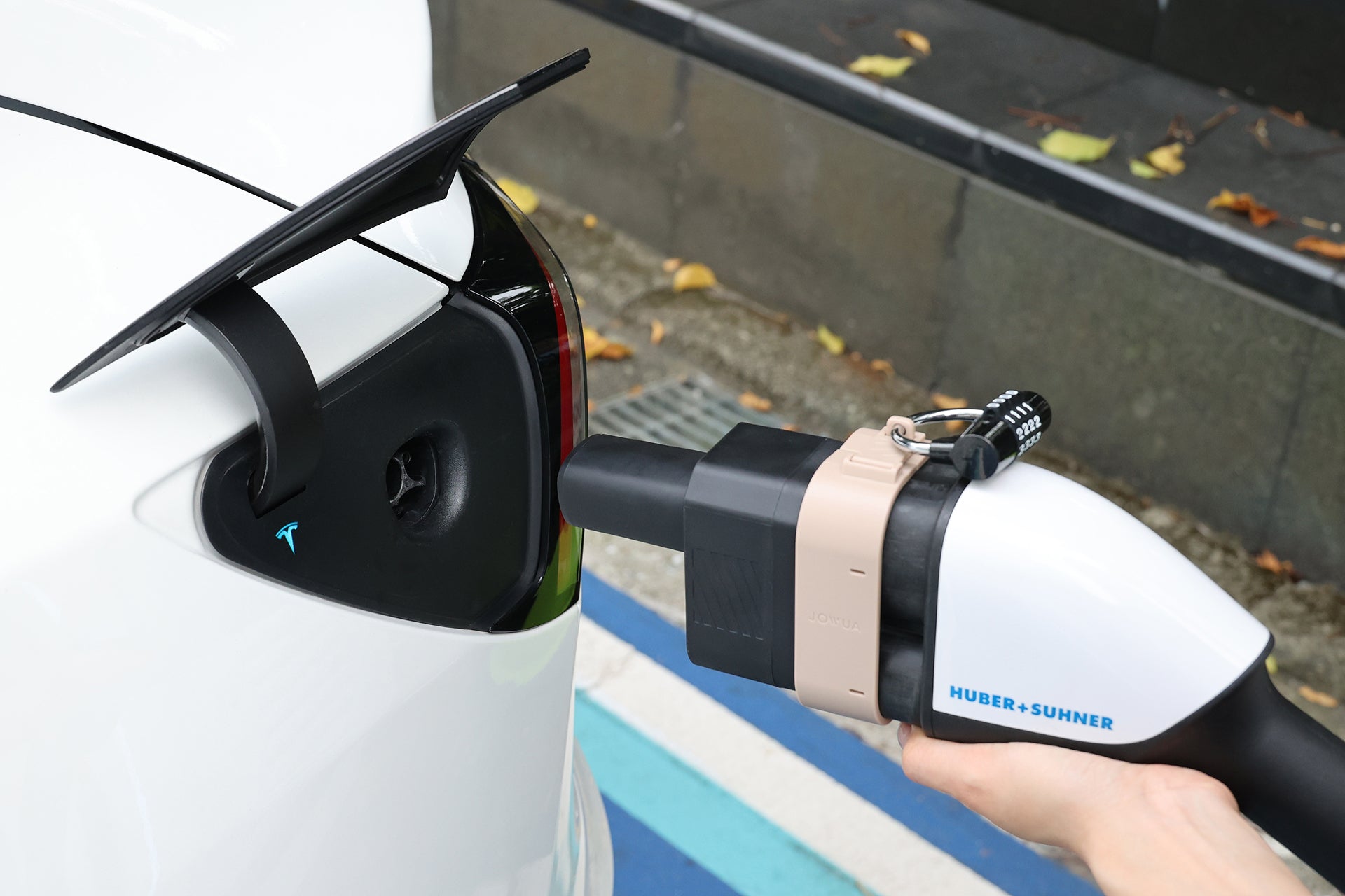 正在充電的白色電動車特寫，JOWUA Taiwan CCS2 to CCS1 充電防拔鎖扣牢牢地將充電槍鎖定在車尾接口處。.