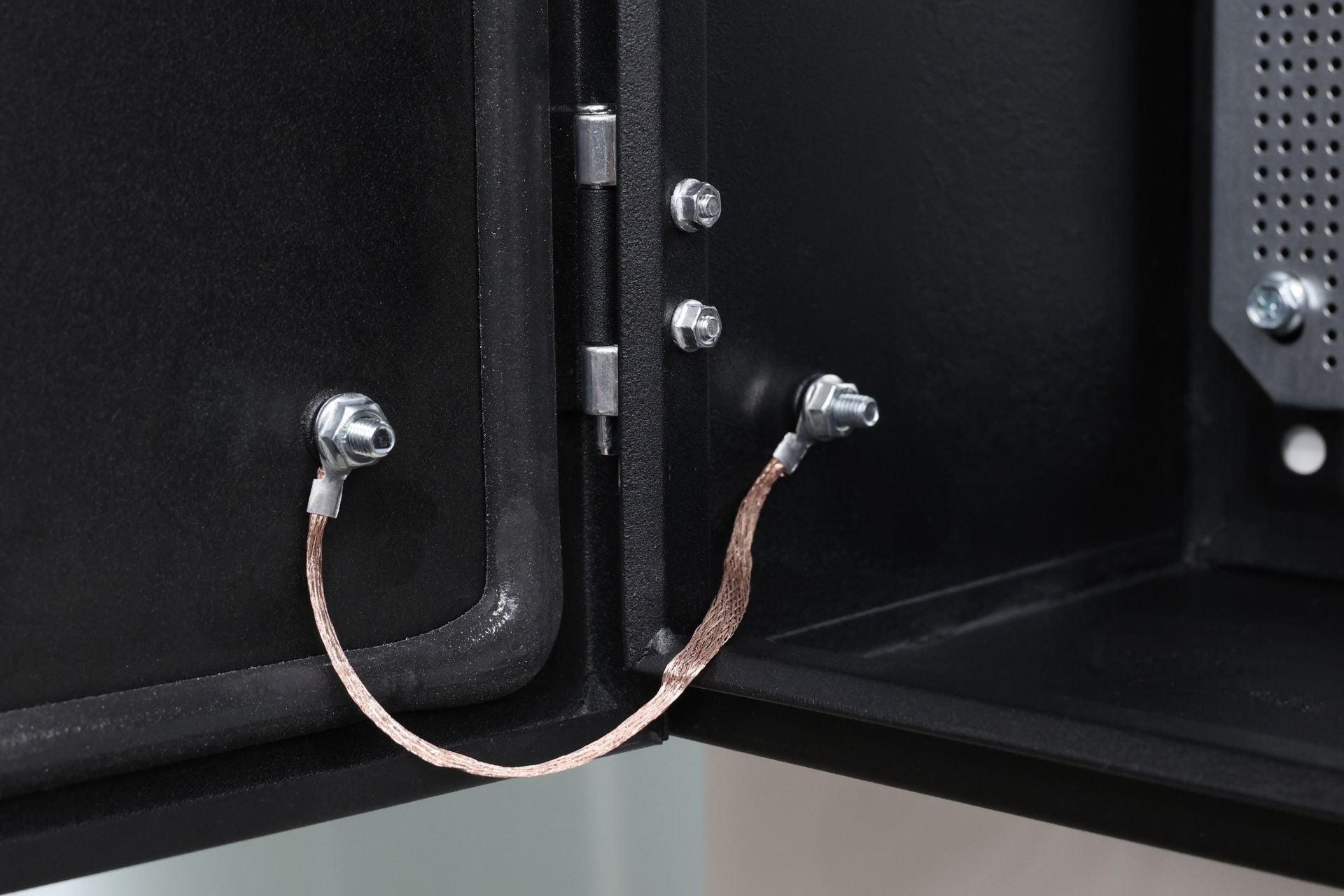 JOWUA Taiwan 配電箱 - 304020 型門內側鉸鏈上兩顆螺栓之間牢固連接的接地線特寫，以確保電氣安全。鋅合金密碼鎖可加強機櫃的安全性。.