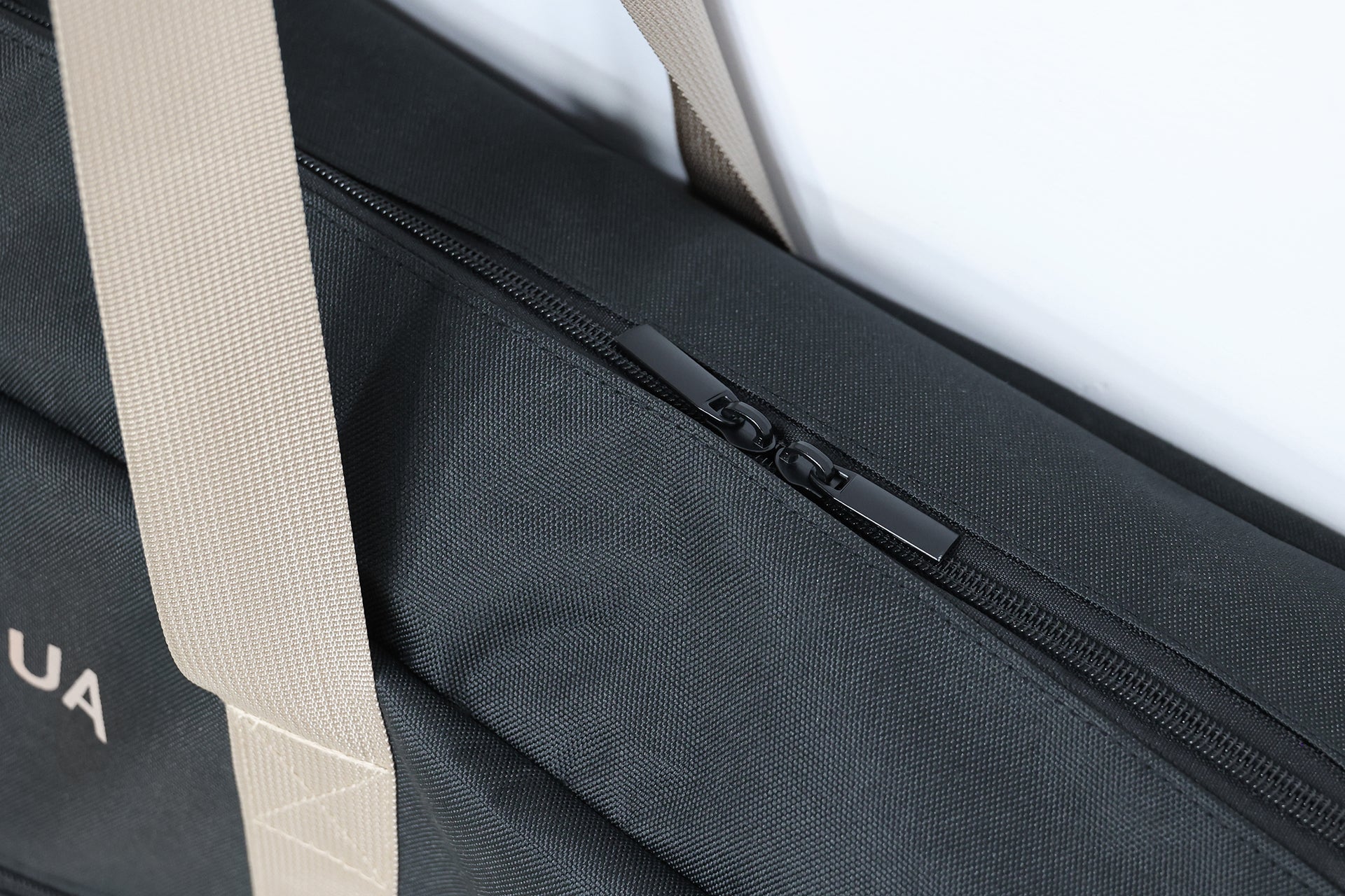 33L 黑色 JOWUA Taiwan 前車廂 & 滑板車專用收納袋特寫，米色肩帶搭配黑色拉鍊。部分 UA 標誌可見，非常適合特斯拉前車廂收納需求。.