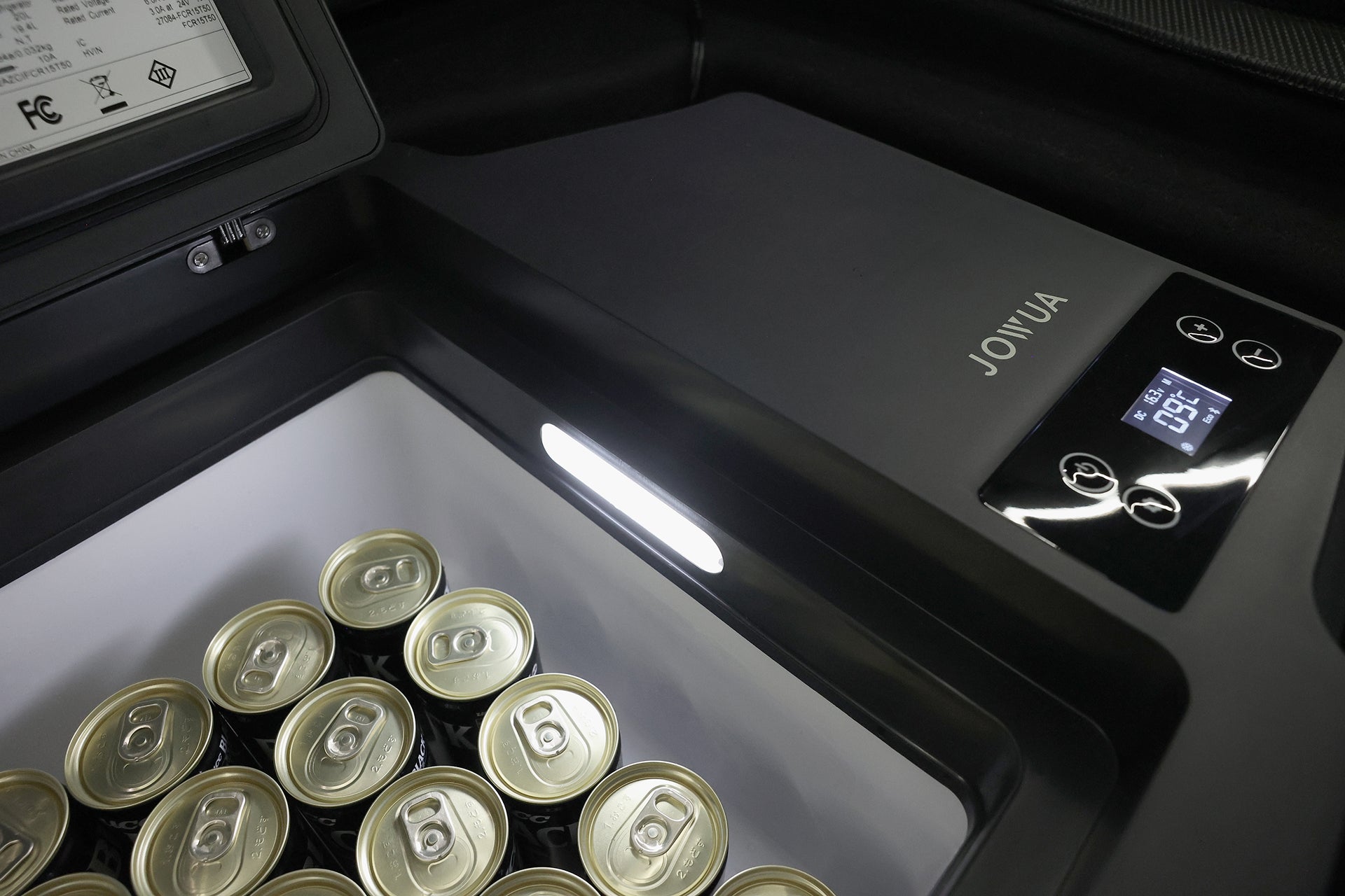 JOWUA 台灣 Type-C 車用行動冰箱 (Model 3 全車系) 的數位顯示器設定為 -1.5°C ，在內部照明燈的照射下，打開蓋子觀看，可以看到裡面有幾個未開封的飲料罐。.