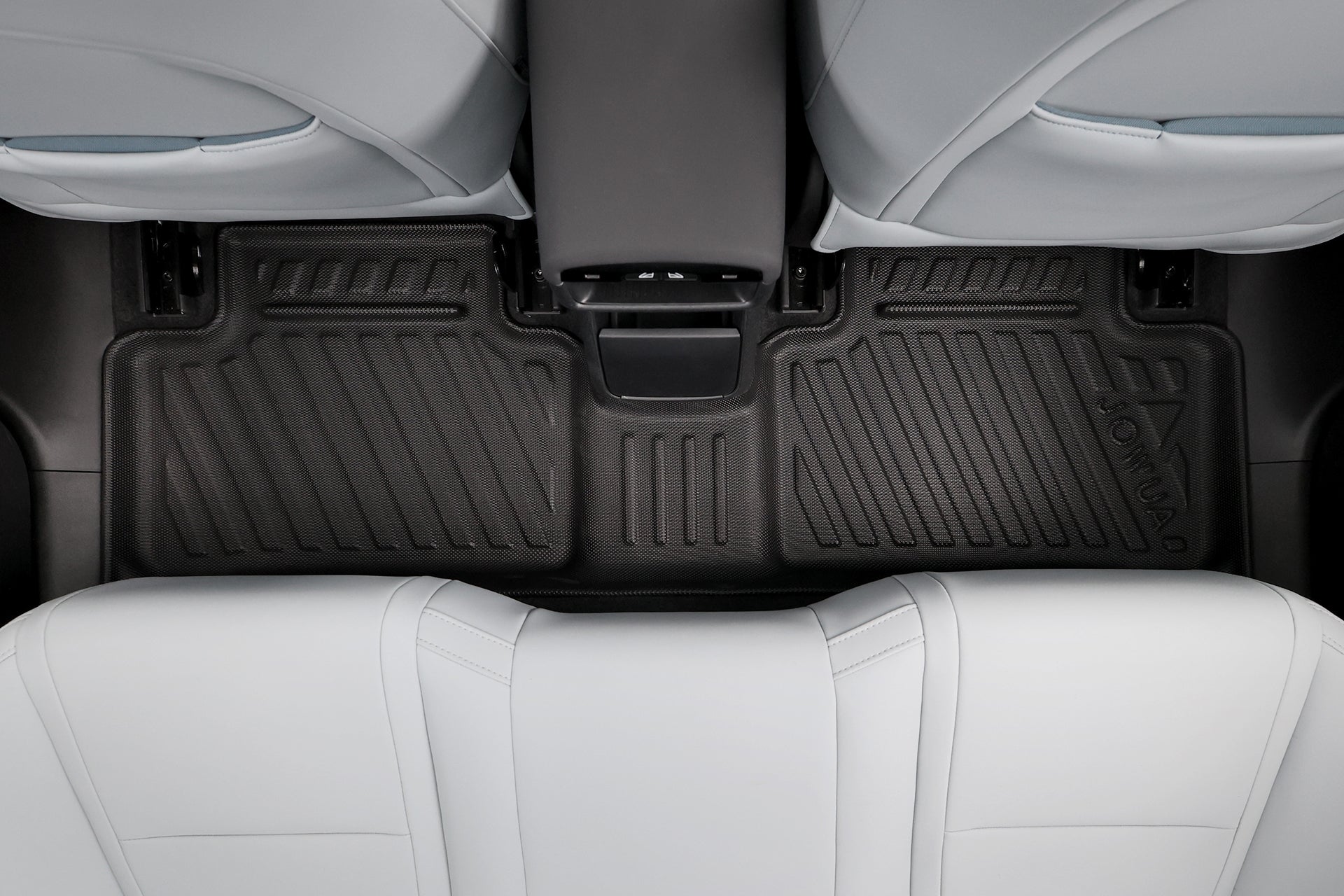 由上而下觀看一輛裝有 JOWUA Taiwan 立體防水腳踏墊的 Volvo EX30 後方地板，兩排淺灰色座椅之間的專利收納設計。黑色全天候墊子具有紋理溝槽和凸起邊緣，可全面防護。.