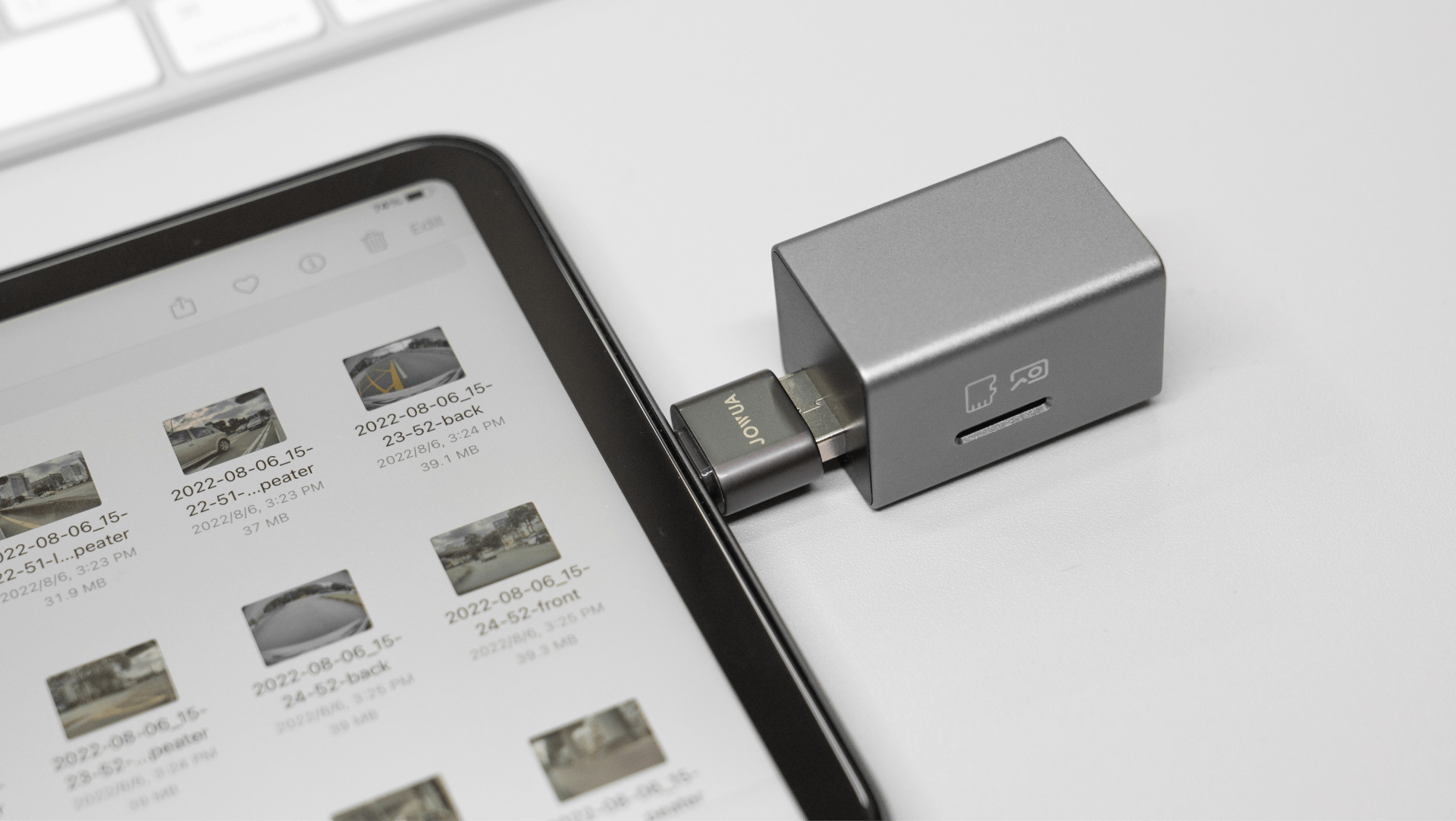 顯示影像的平板電腦透過小型轉接器連接到JOWUA台灣手套專用箱3埠集線器+讀卡機。裝置位於淺色表面上，部分鍵盤可見，提供增強的 USB3 抗干擾連接。.